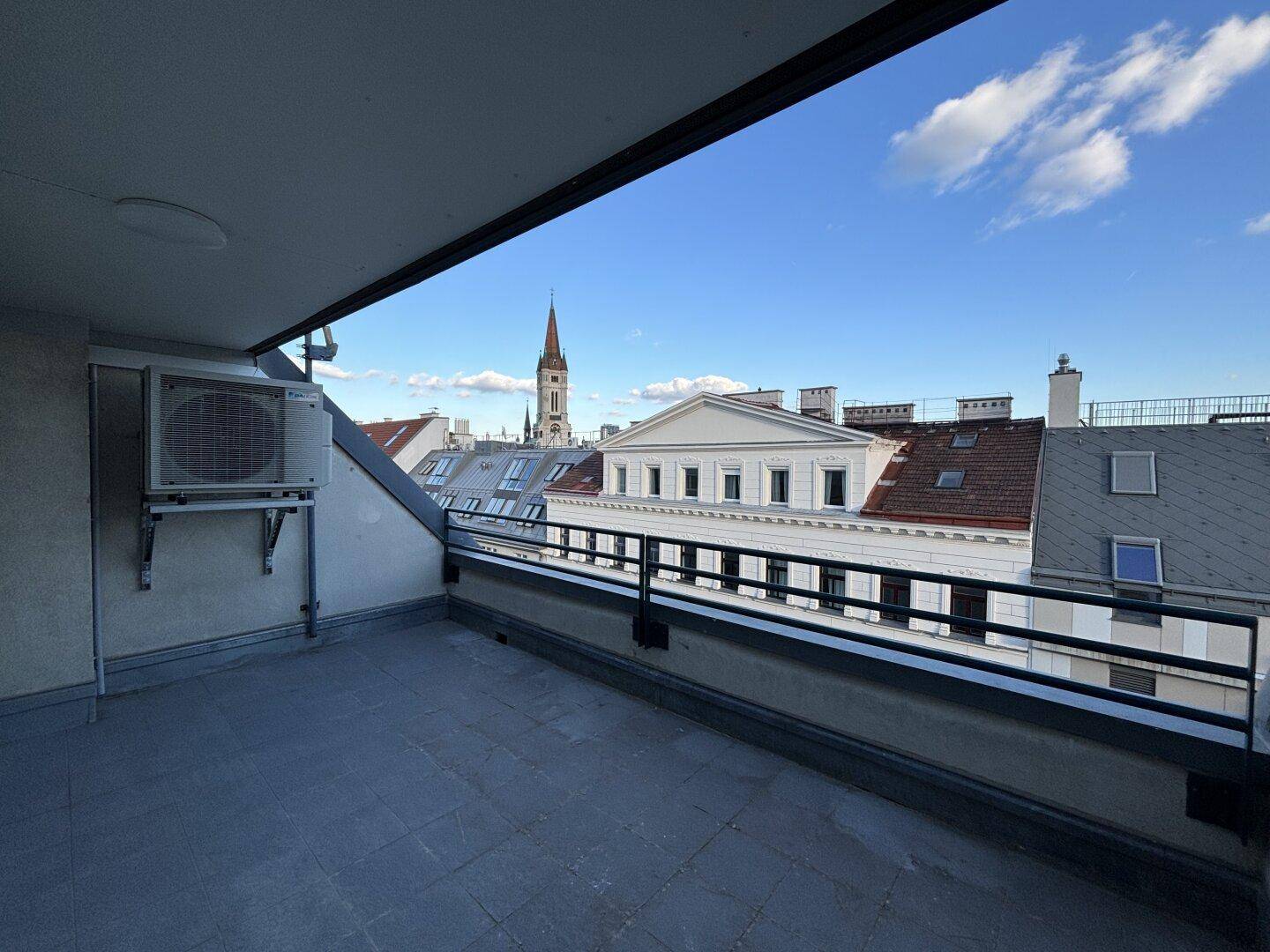 Unmöblierte Dachterrasse mit weitem Blick über die Stadt und den Himmel.