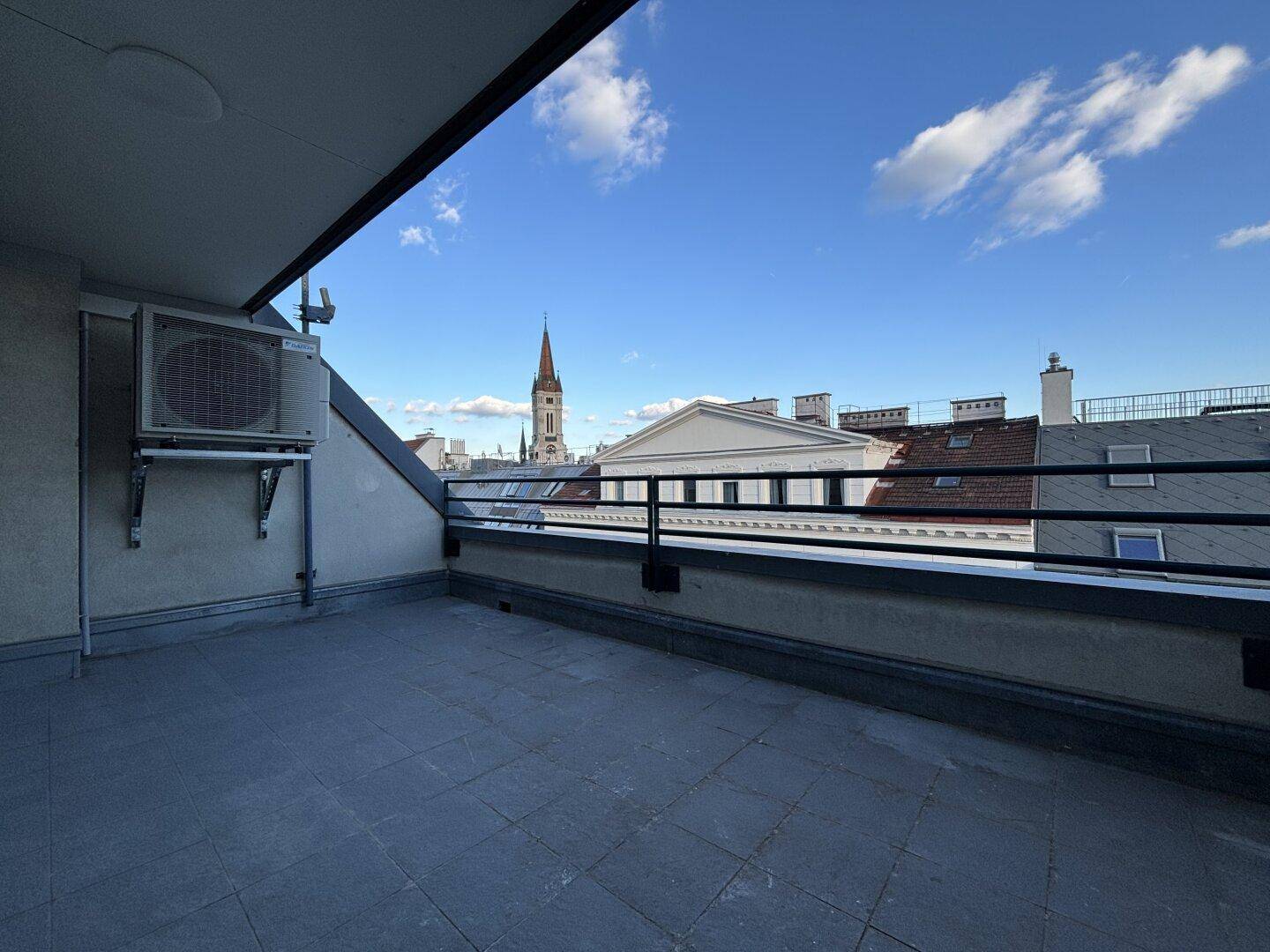 Unmöblierte Dachterrasse mit Stadtblick und Geländer, bereit zur Gestaltung.