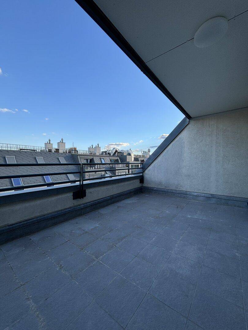 Dachterrasse mit Blick auf die umliegenden Dächer und den blauen Himmel.