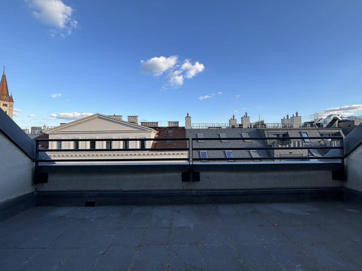 Geräumige, unmöblierte Dachterrasse mit weitem Blick über die Dächer der Stadt.