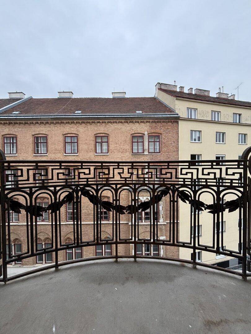 Blick vom Balkon mit kunstvollem schmiedeeisernem Geländer auf die umliegenden historischen Gebäude.