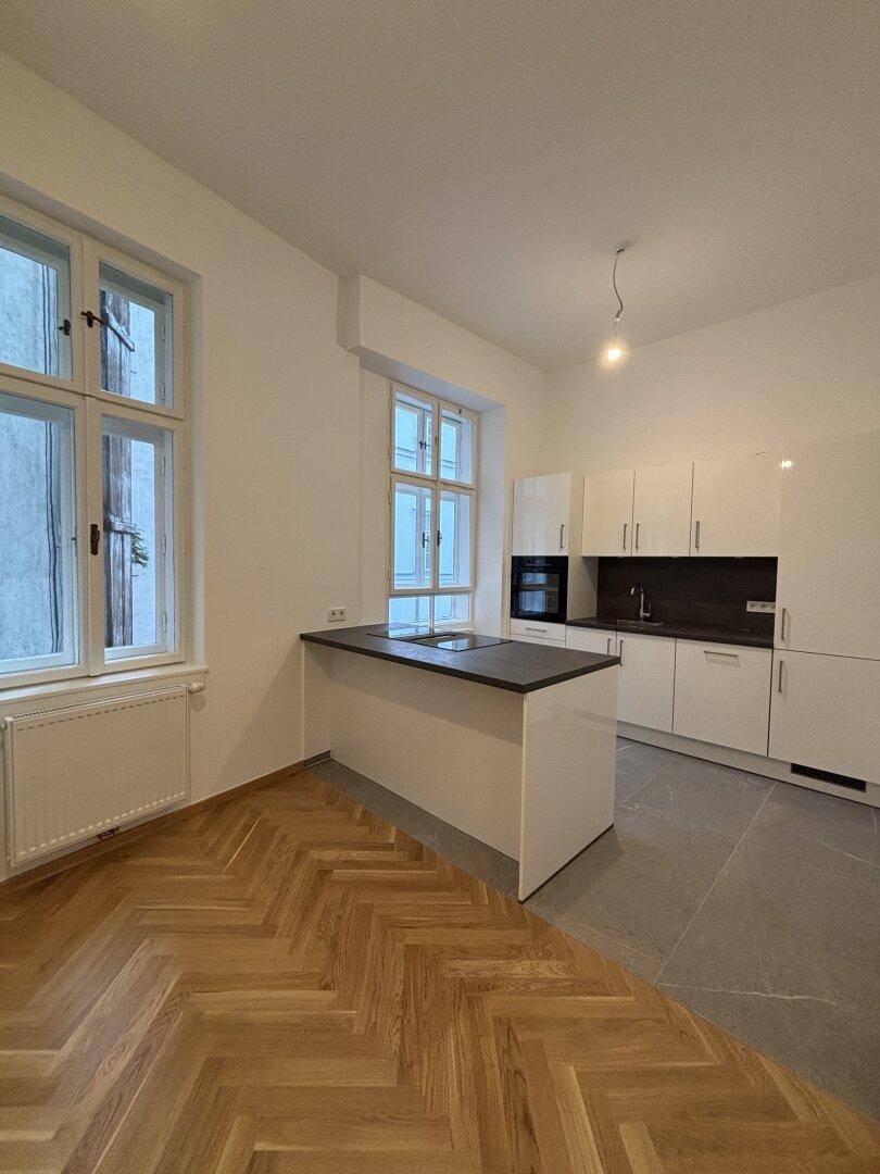 Detailansicht der modernen Küche mit integriertem Backofen und Induktionskochfeld auf der Kücheninsel.