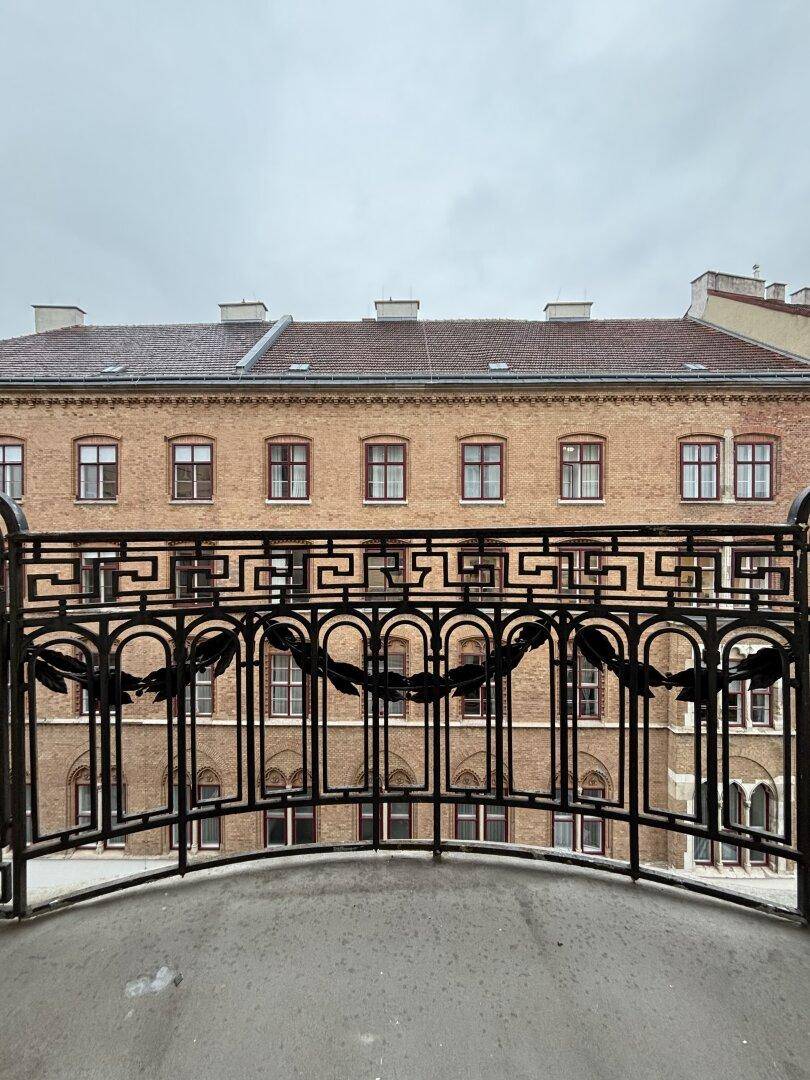 Blick vom Balkon mit kunstvollem schmiedeeisernem Geländer auf die umliegenden historischen Gebäude.