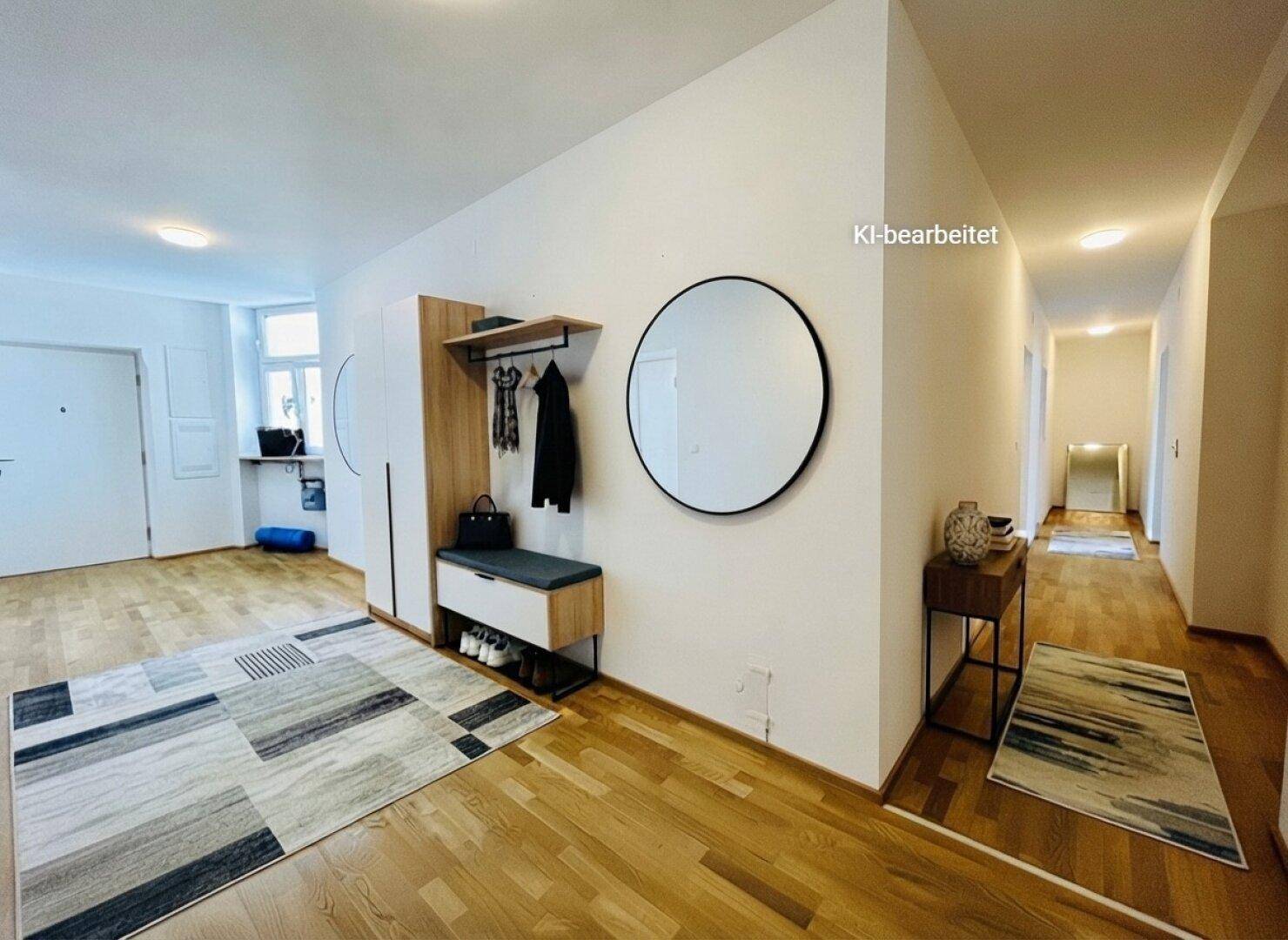 Heller Eingangsbereich mit Holzparkett, Garderobe und einem runden Spiegel.