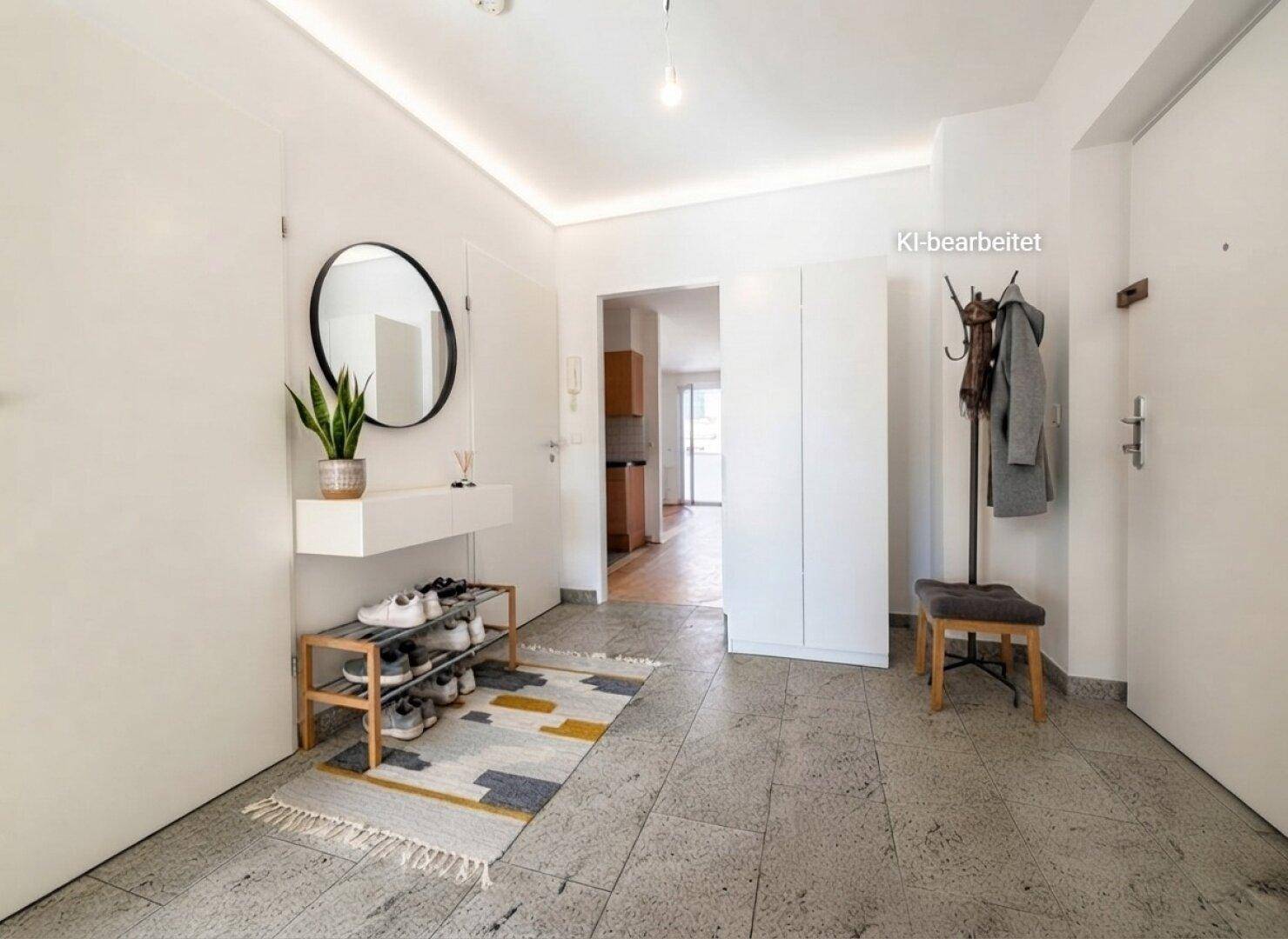 Heller Eingangsbereich mit Fliesenboden, Garderobe und modernem Spiegel.