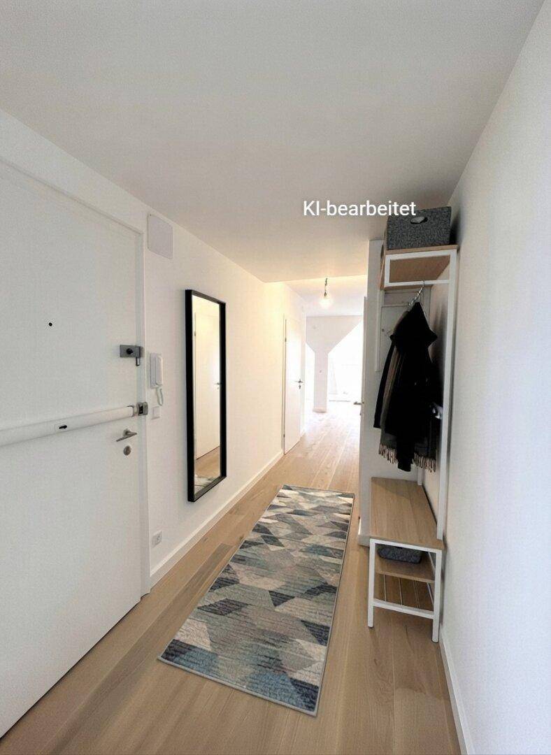 Heller Flur mit Holzboden, weiß gestrichenen Wänden und praktischer Garderobe.