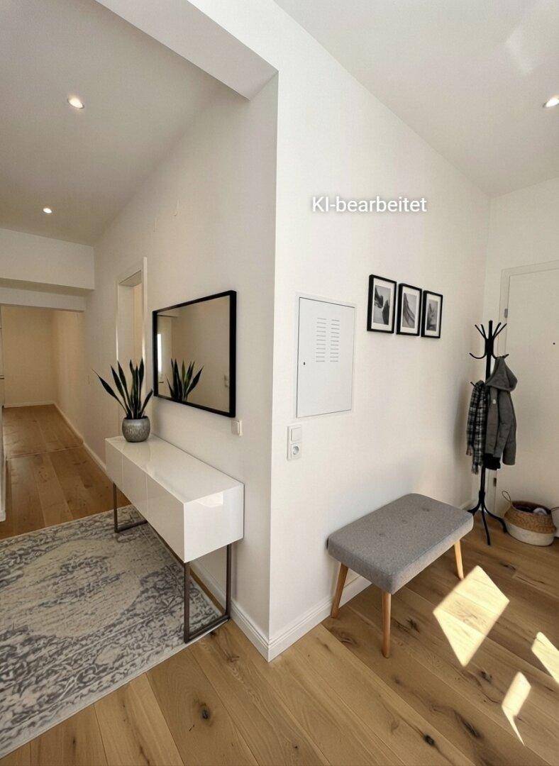Heller Eingangsbereich mit Holzboden, modernem Konsolentisch und Garderobe.