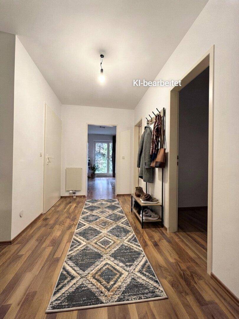Flur mit Holzboden, Teppichläufer und Garderobe, die zu weiteren Räumen führt.