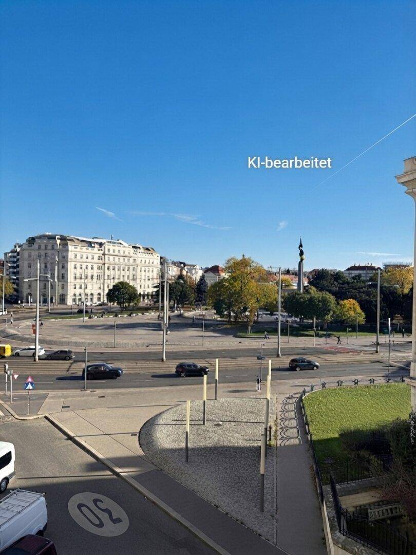 Blick auf eine belebte Stadtkreuzung mit Gebäuden und Fahrzeugen unter klarem blauem Himmel.