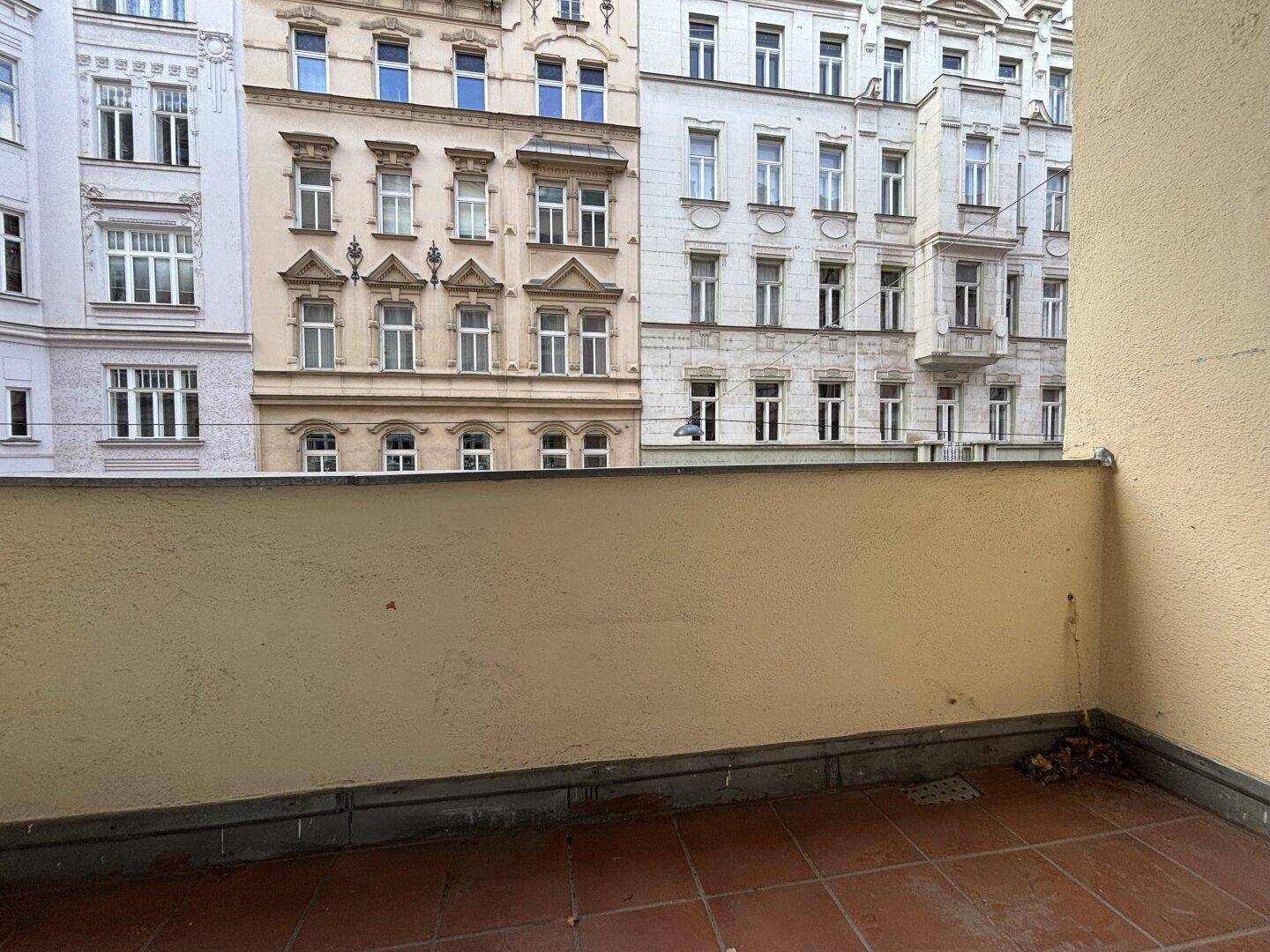 Kleiner Balkon mit Terrakottafliesen und Blick auf die umliegenden historischen Gebäude der Stadt.