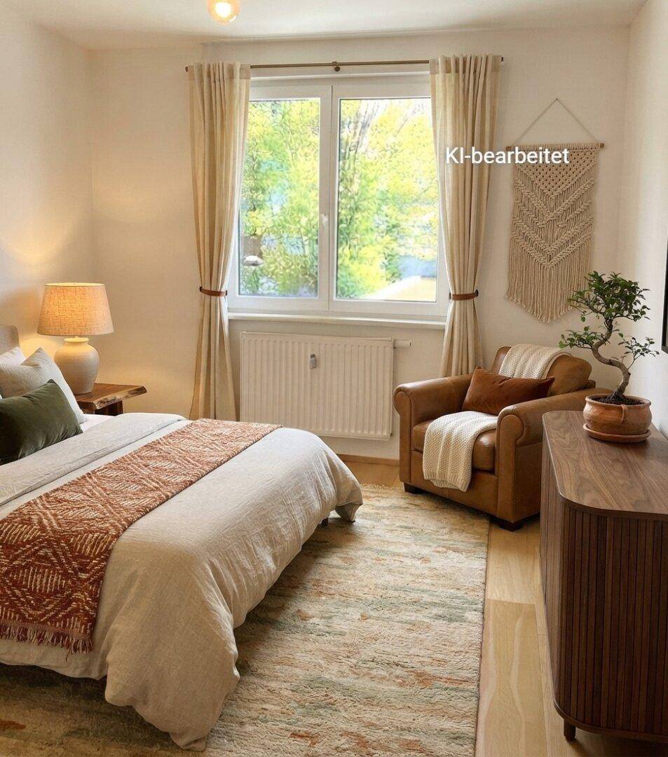 Helles Schlafzimmer mit bequemen Bett, Sessel und Fenster mit Blick ins Grüne.
