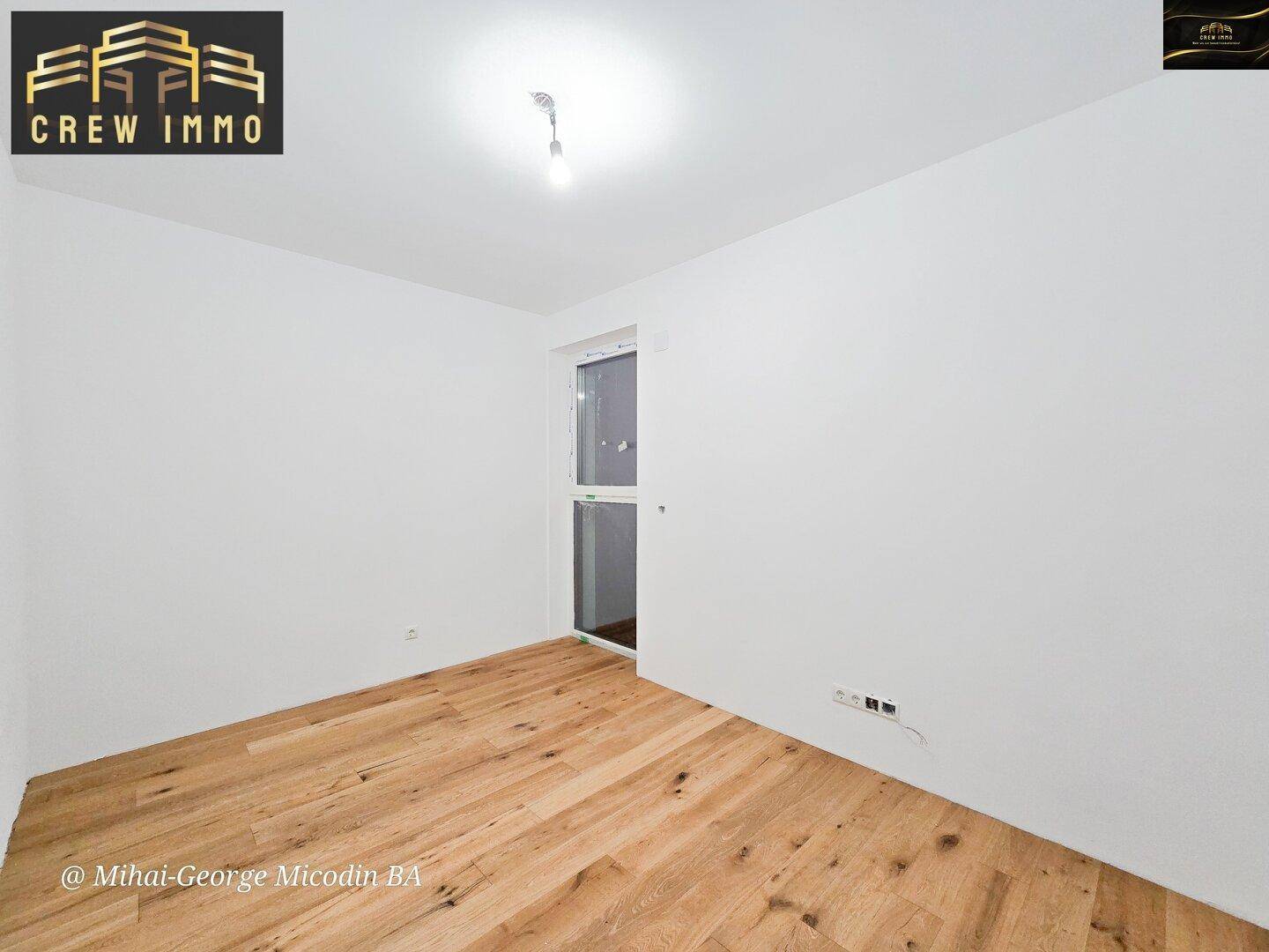 Leeres Schlafzimmer mit Holzboden und einer Tür, die nach draußen führt, ideal für frische Luft.