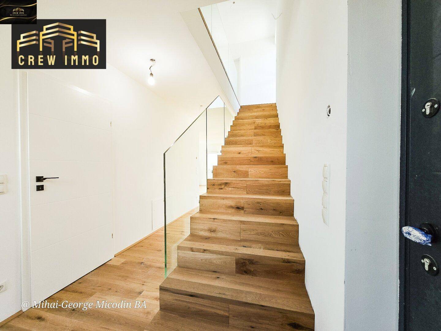 Moderne Holztreppe mit eleganter Glasbrüstung, die das Erdgeschoss mit dem Obergeschoss verbindet.