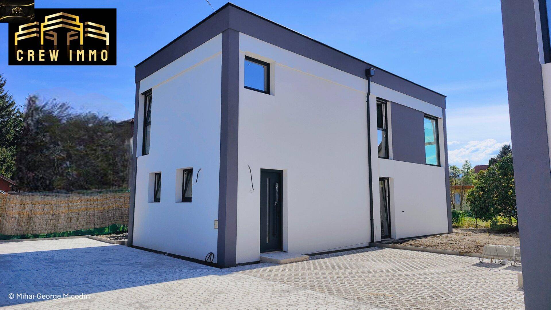 Seitenansicht des modernen Neubaus mit klaren Linien und großen Fenstern in einer ruhigen Umgebung.