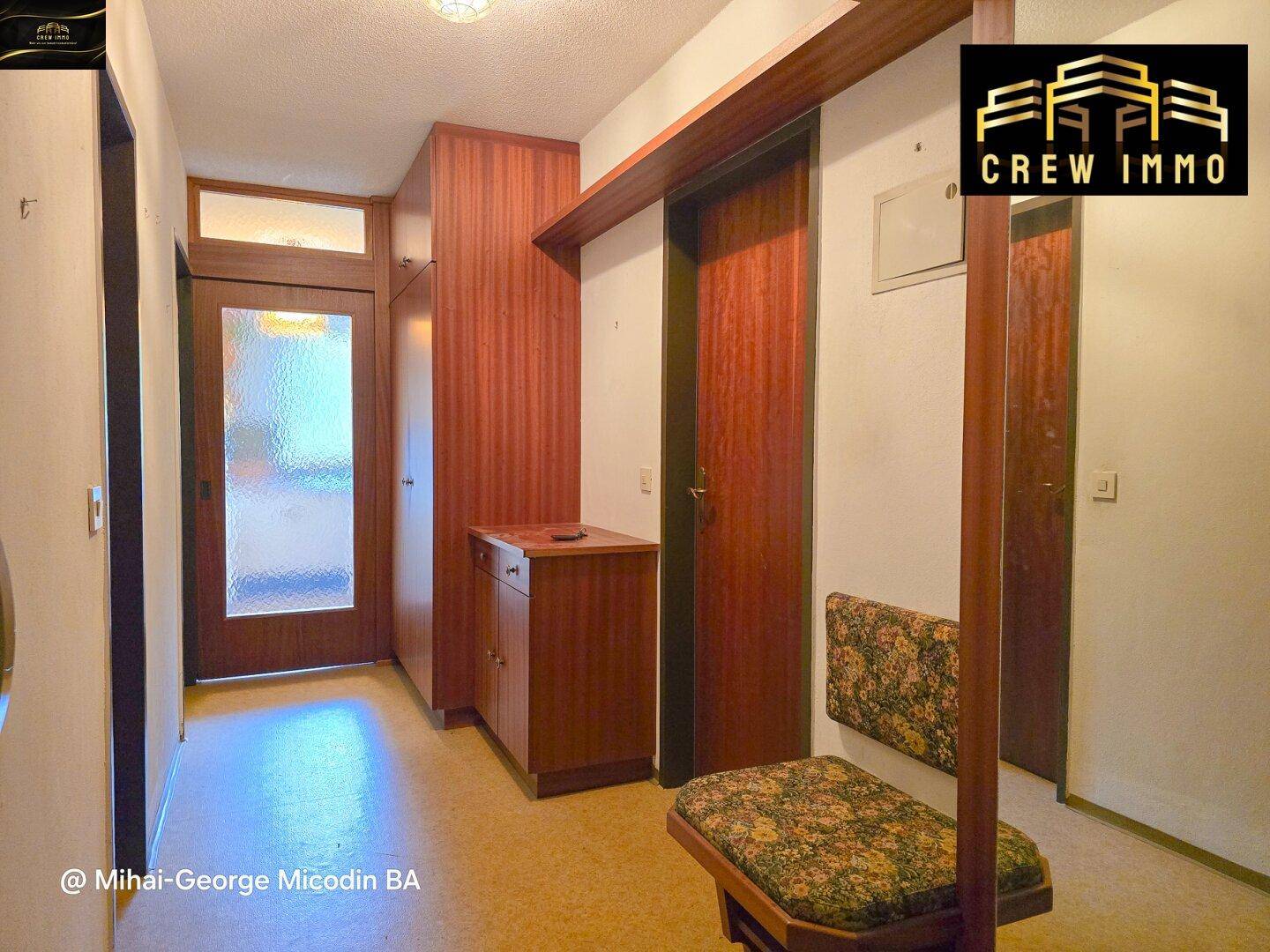 Eingangsbereich mit Holzvertäfelung, Garderobe und gemustertem Bodenbelag.