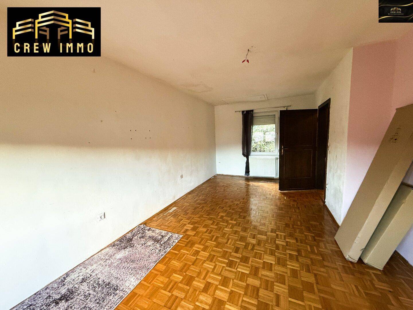 Helles Zimmer mit Parkettboden und Fenster, ideal als Schlaf- oder Gästezimmer nutzbar.