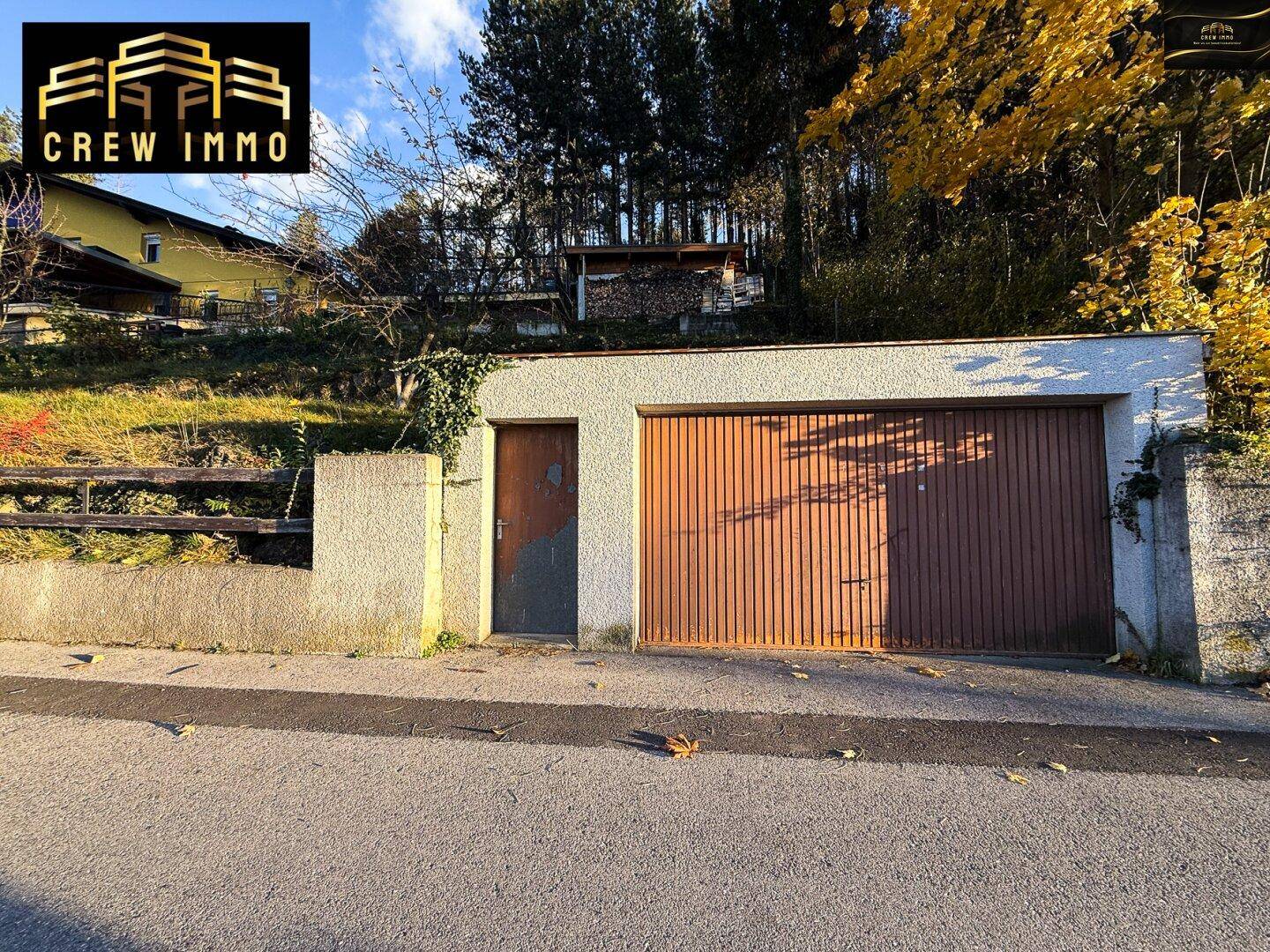 Garage mit Holztor und separatem Eingang, direkt an der Straße gelegen.