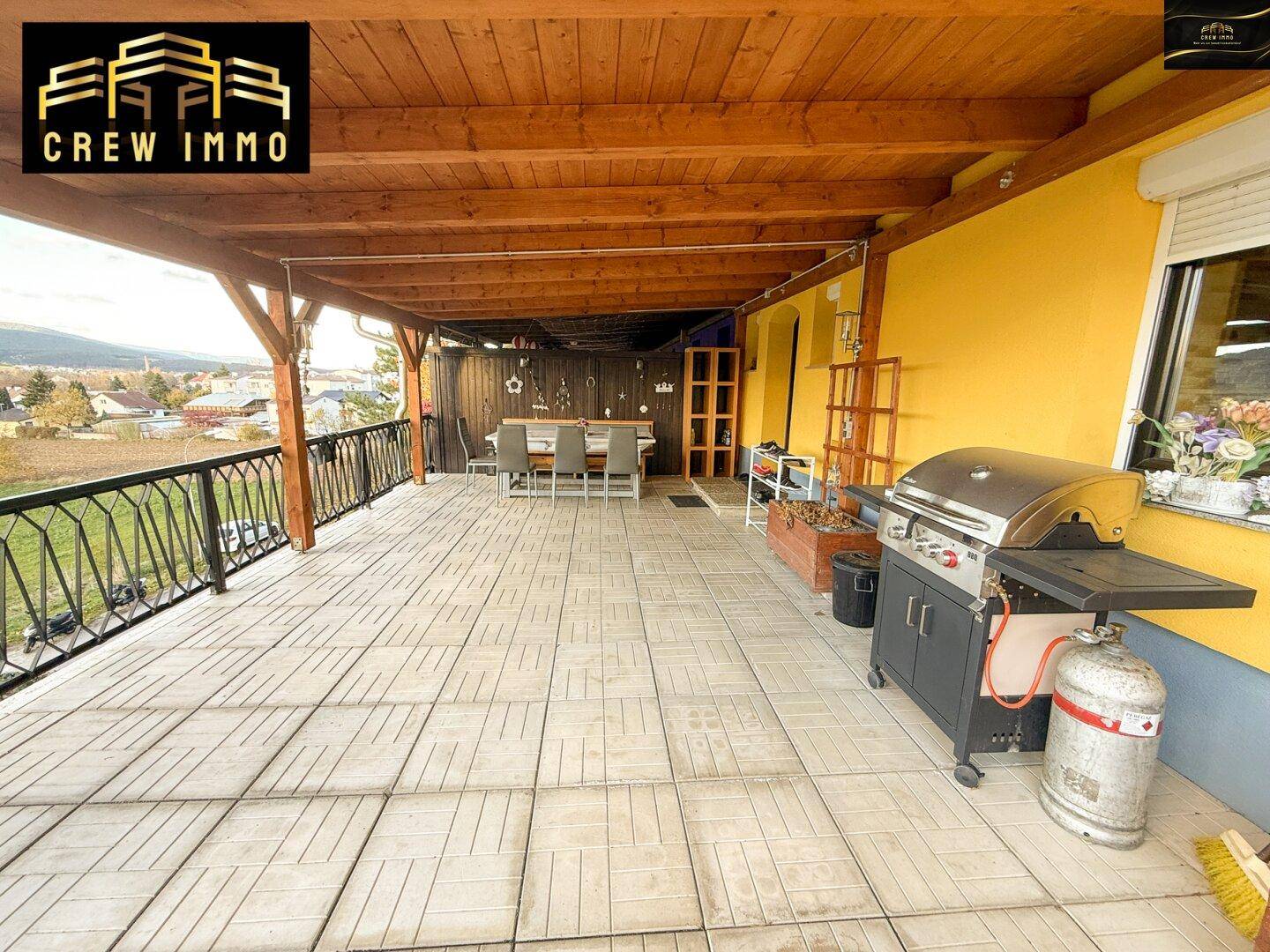 Überdachte Terrasse mit Grillbereich, Essplatz und weitem Blick auf die Umgebung.