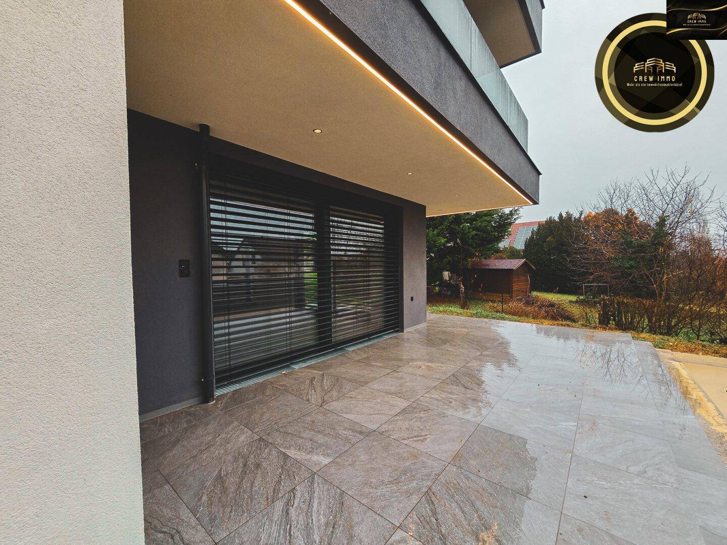 Große geflieste Terrasse mit modernen Schiebetüren und integrierter Deckenbeleuchtung.