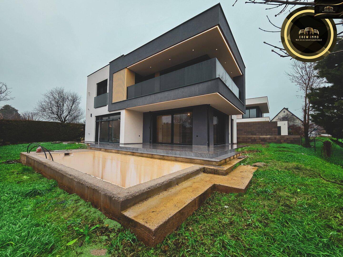 Moderne Hausarchitektur mit einem unfertigen Poolbereich und umliegender Grünfläche.