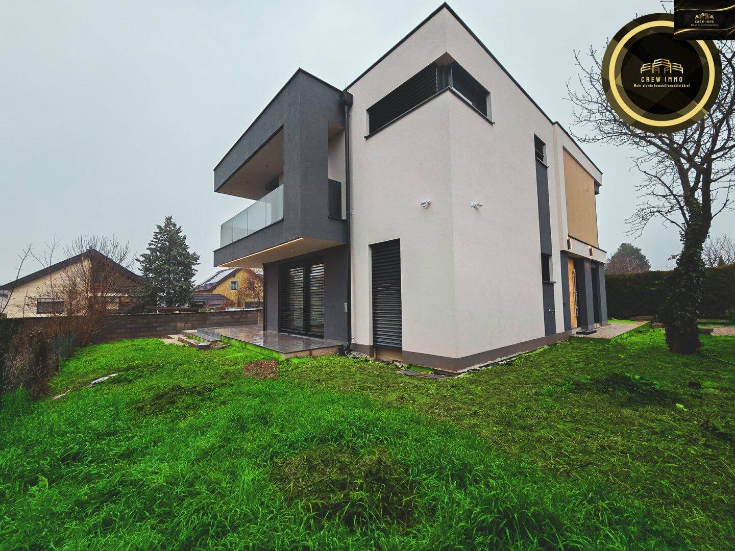 Seitenansicht der modernen Villa mit weißer Fassade und weitläufiger Rasenfläche.