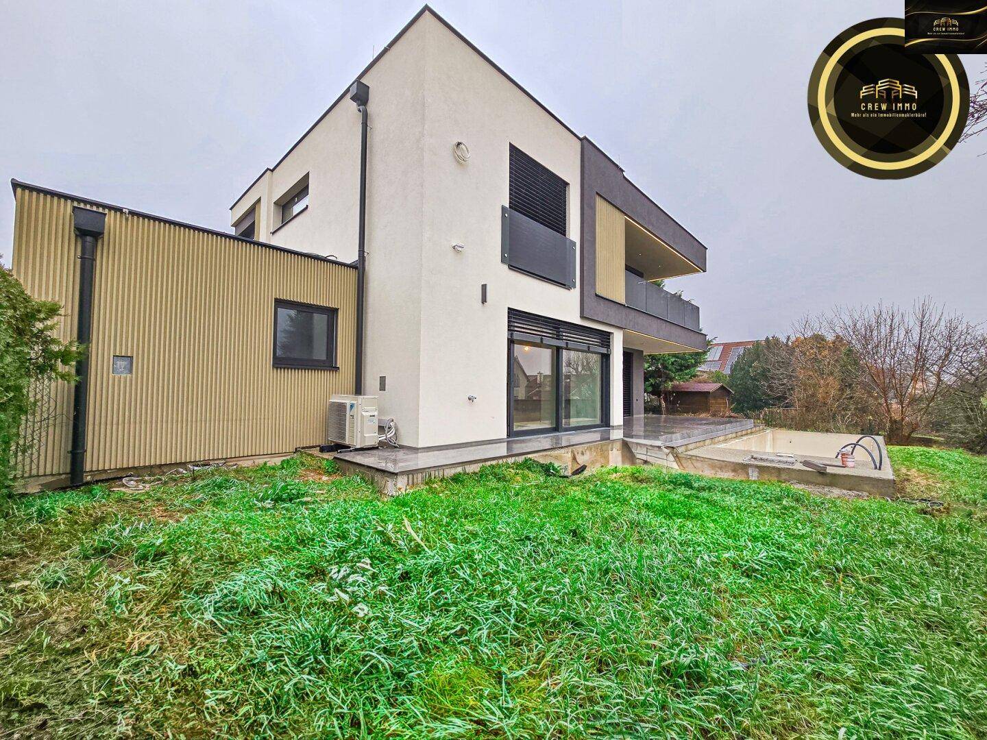 Rückansicht der modernen Villa mit großem Garten und sichtbarer Klimaanlage.