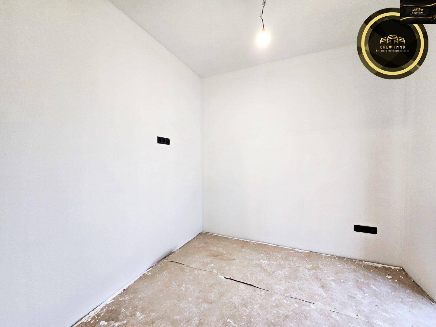 Unfertiger Raum mit rohem Boden und weißen Wänden, bereit für individuelle Gestaltung.