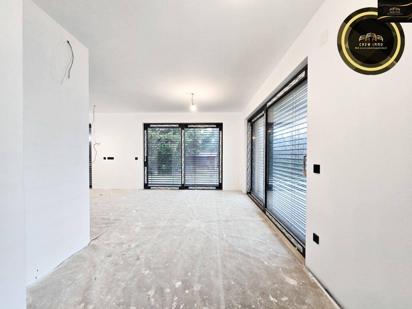 Unfertiger Essbereich mit rohem Boden und großen Fenstern, bereit zur Gestaltung.