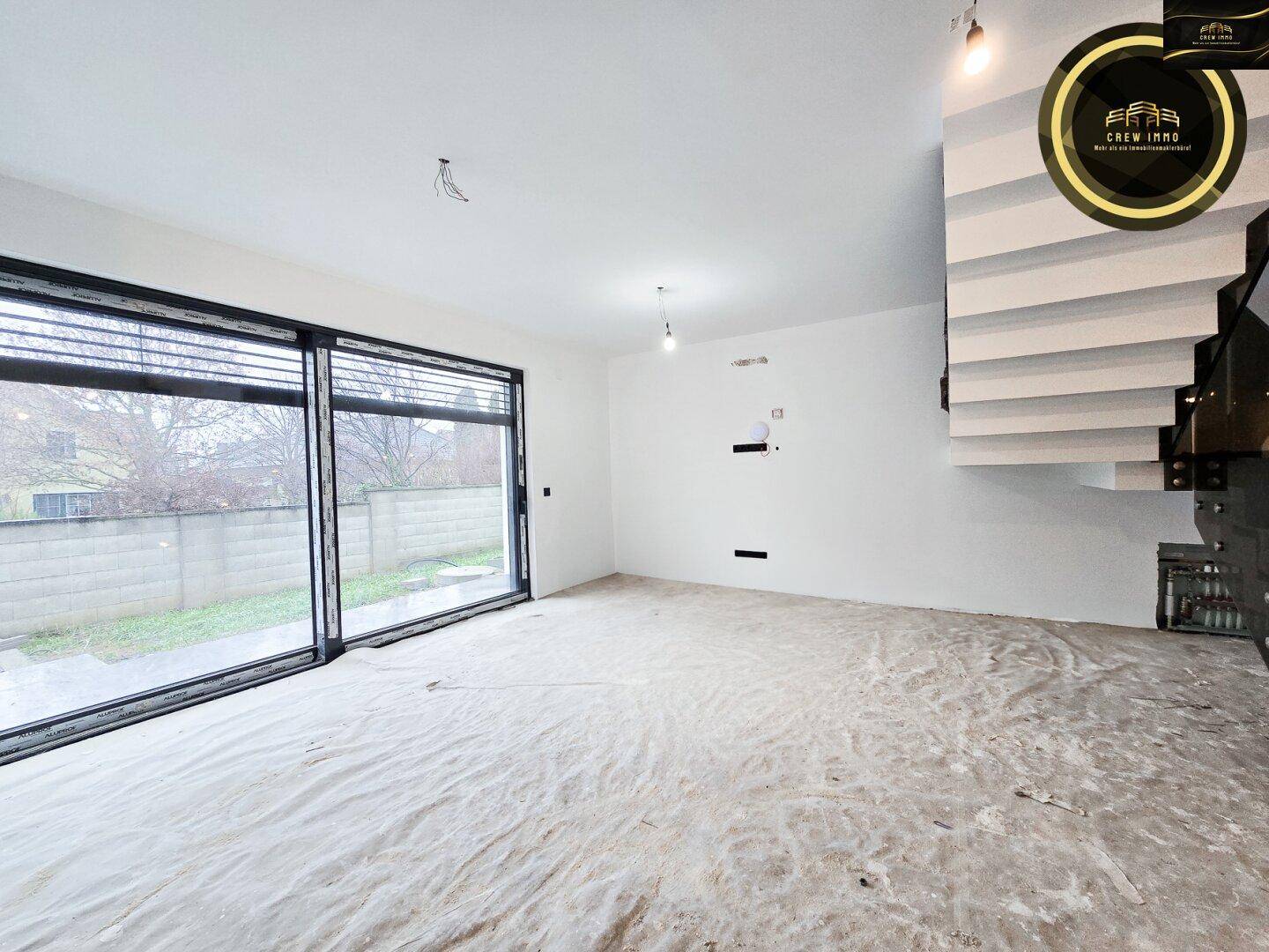 Geräumiges, unfertiges Wohnzimmer mit großen Schiebetüren und Blick in den Garten.