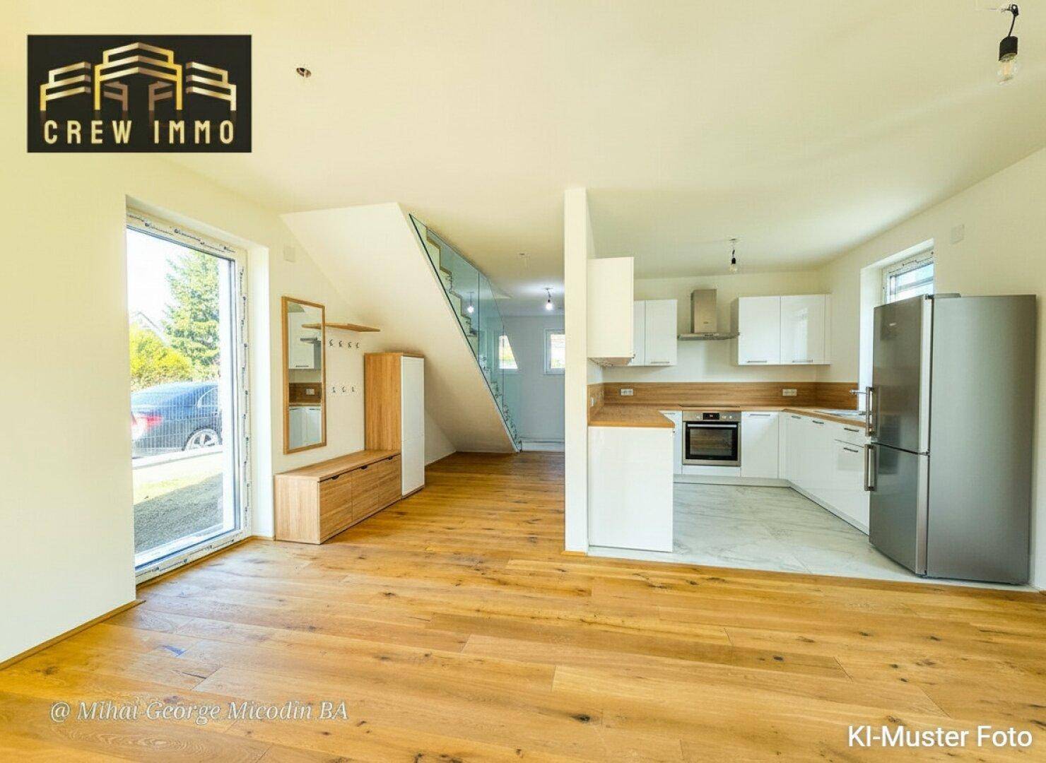 Heller offener Eingangsbereich mit moderner Einbauküche und Holzfußboden.