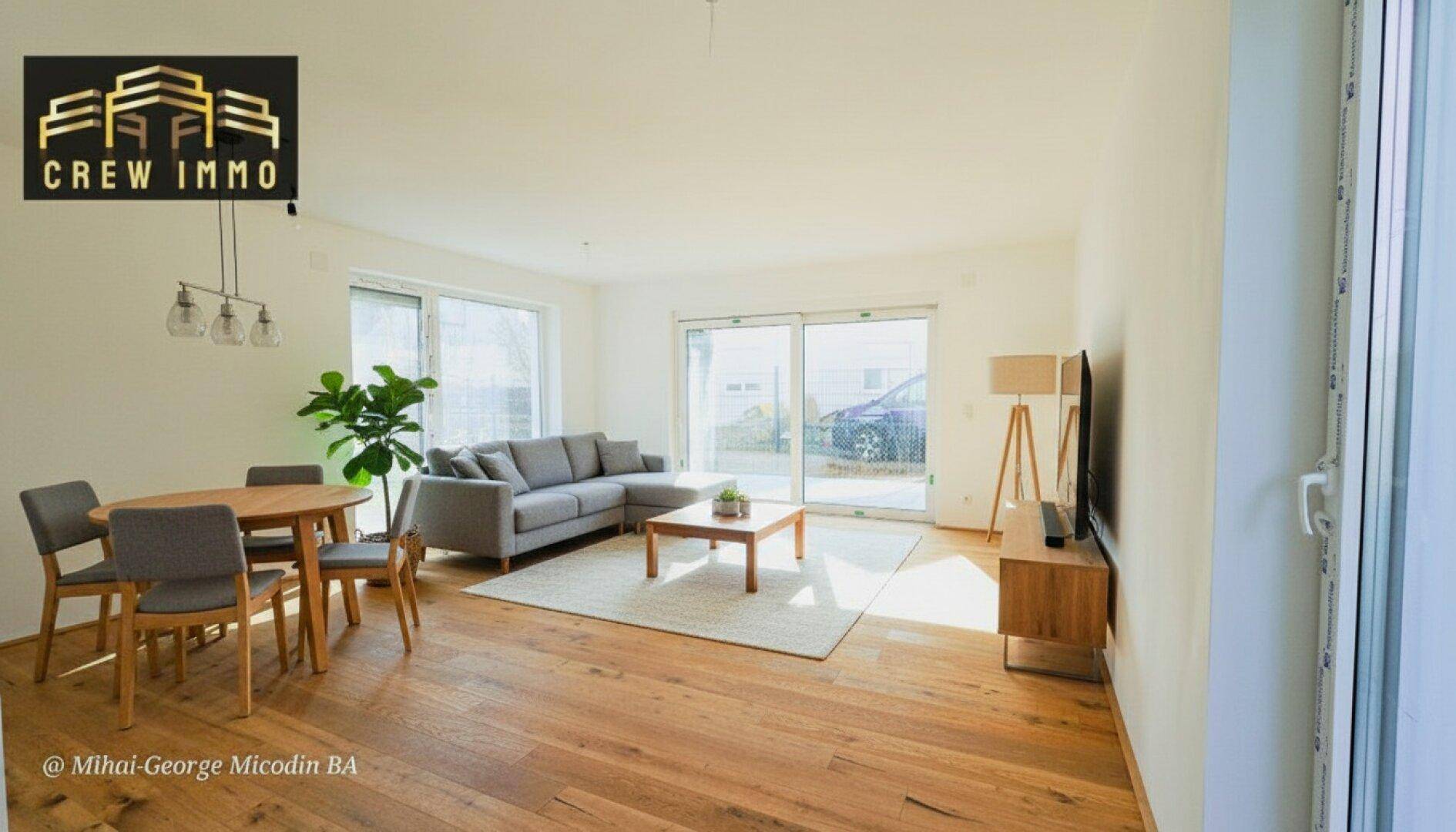 Lichtdurchfluteter Wohn- und Essbereich mit Holzboden, bequemer Couch und Zugang zum Garten.