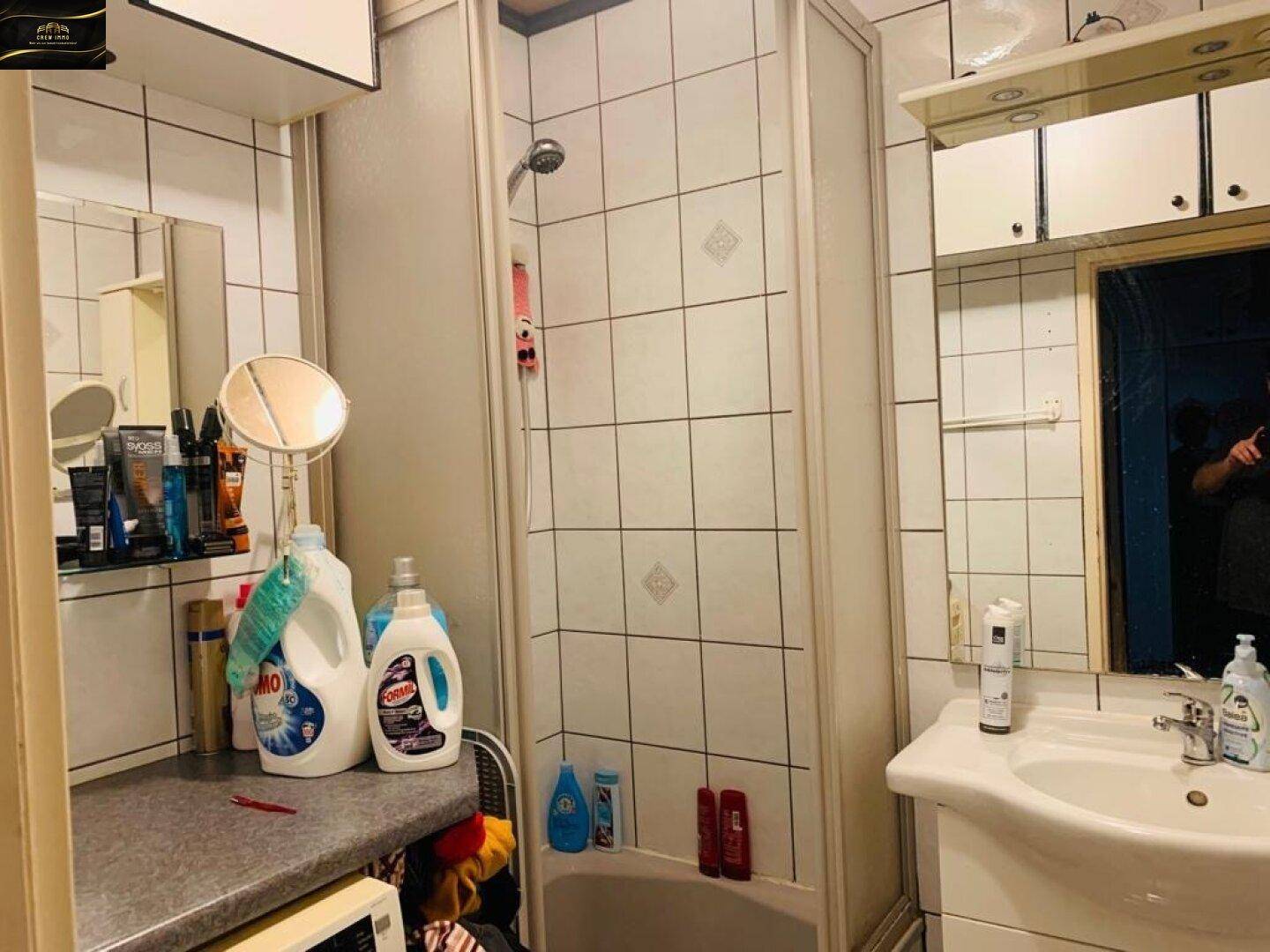 Funktionales Badezimmer mit Duschkabine, Waschbecken und gefliesten Wänden.