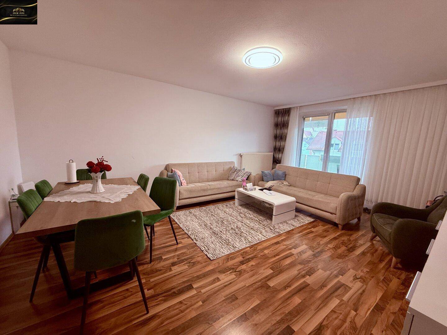 Geräumiger Wohn- und Essbereich mit Holzboden, beigen Sofas und einem Esstisch.