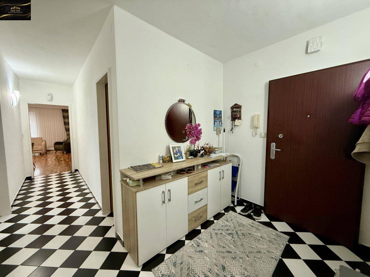 Eingangsbereich mit auffälligem schwarz-weißem Fliesenboden und einer Garderobe.