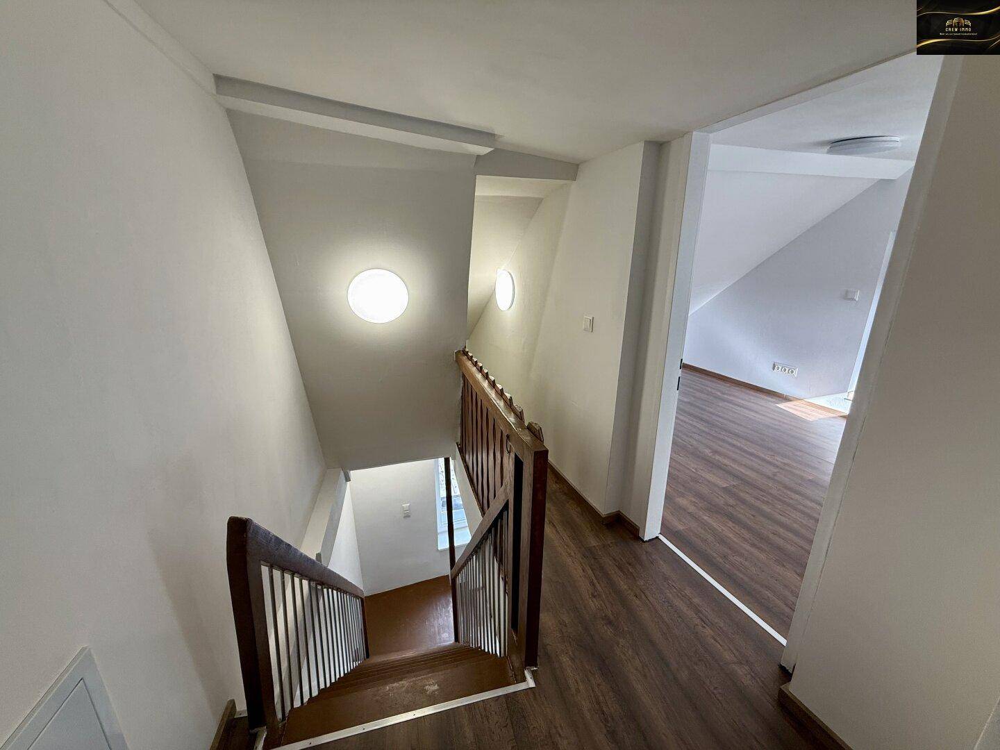 Treppenaufgang mit Holzstufen und Laminatboden, der in die obere Etage führt.
