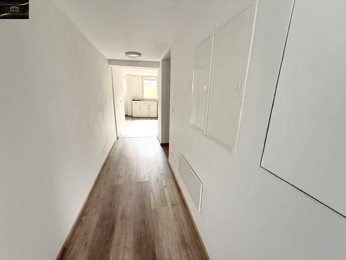 Langer, heller Flur mit Laminatboden, der zu den Wohnbereichen des Hauses führt.