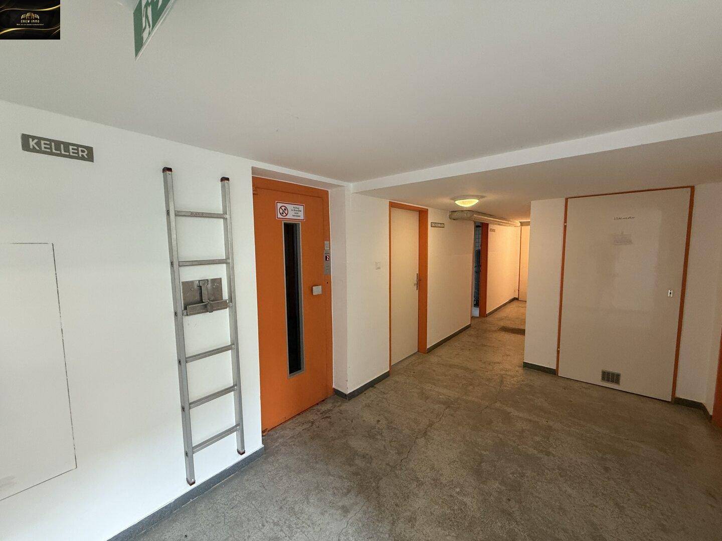 Langer Flur im Kellergeschoss mit Aufzug und Zugang zu den einzelnen Kellerräumen.