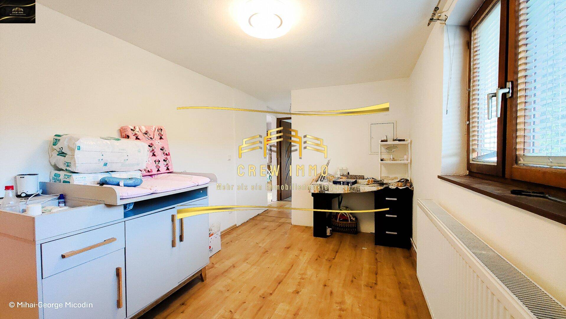 Vielseitiger Raum, eingerichtet als Kinderzimmer und Arbeitsbereich mit Holzboden.