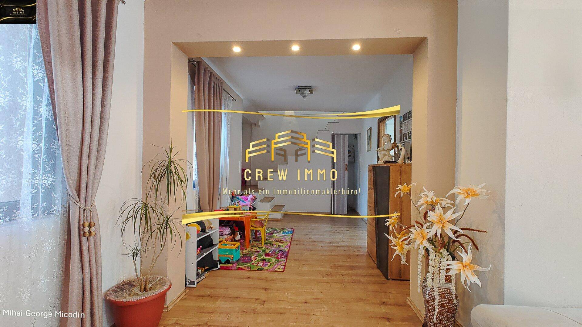 Heller Durchgangsbereich mit Holzboden, der zu einem Spielbereich für Kinder führt.