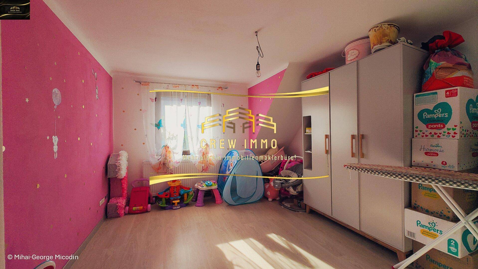 Farbenfrohes Kinderzimmer mit rosa Wänden, Spielzeug und einem Fenster für Tageslicht.