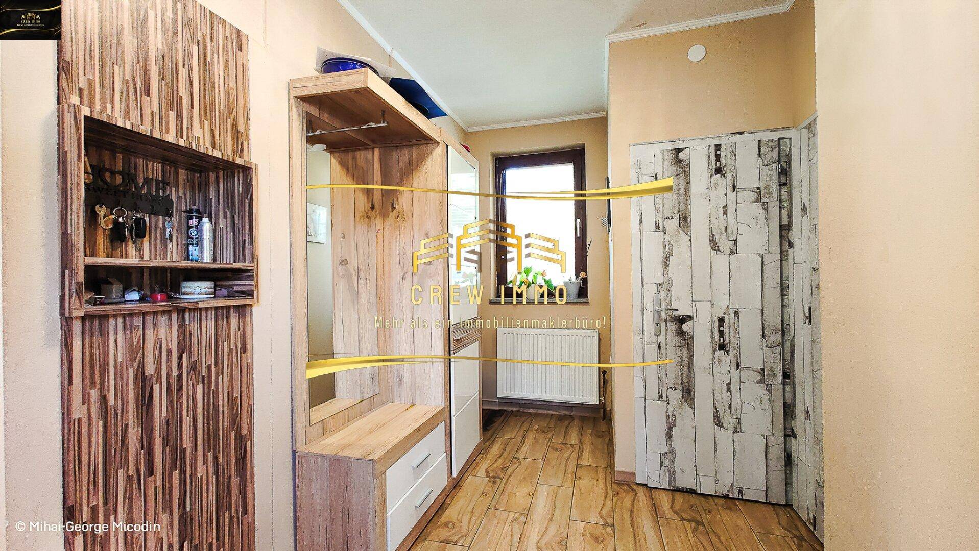 Eingangsbereich mit praktischer Garderobe aus Holz und einem Fenster für natürliches Licht.
