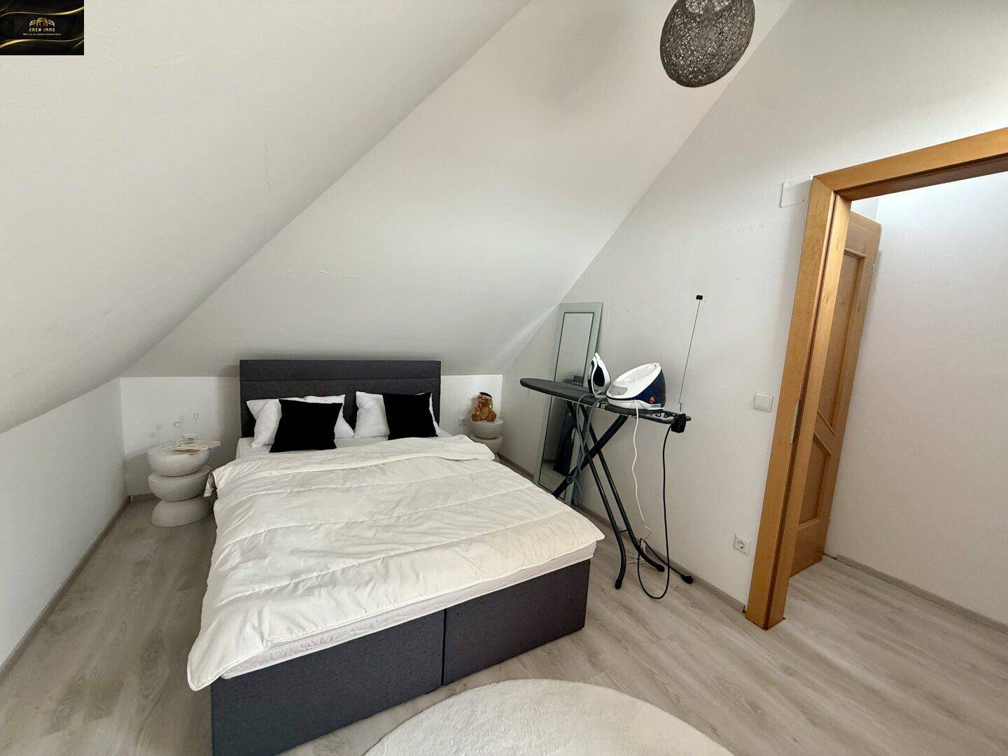 Schlafzimmer im Dachgeschoss mit Doppelbett, schräger Decke und Laminatboden.