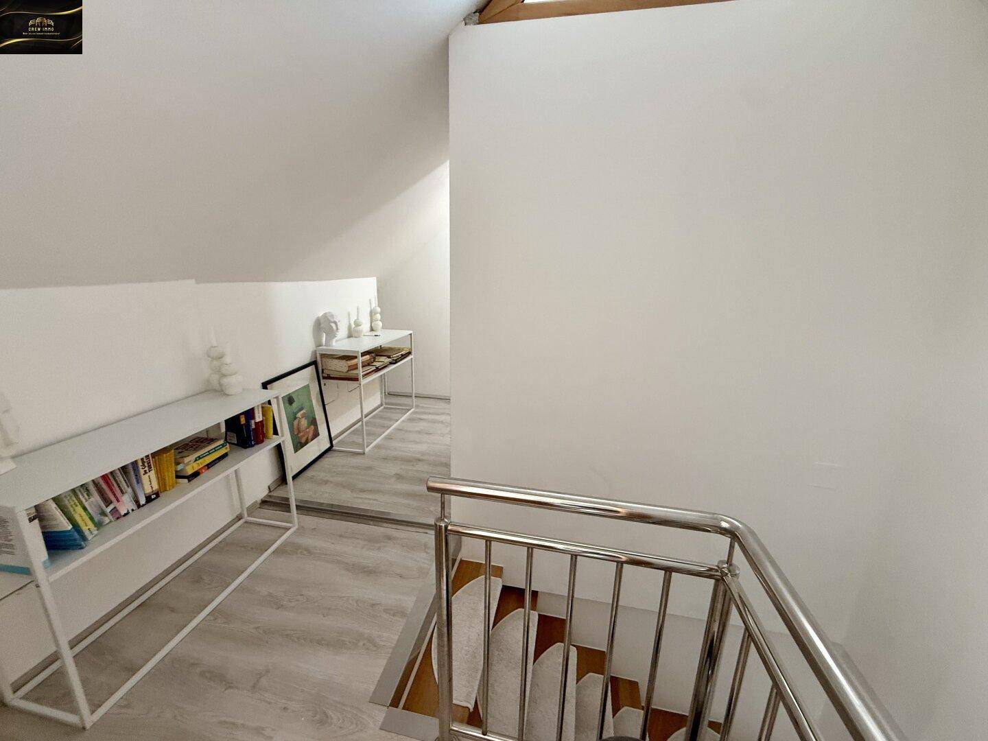 Heller Treppenabsatz im Dachgeschoss mit Bücherregalen und Blick auf die Treppe.