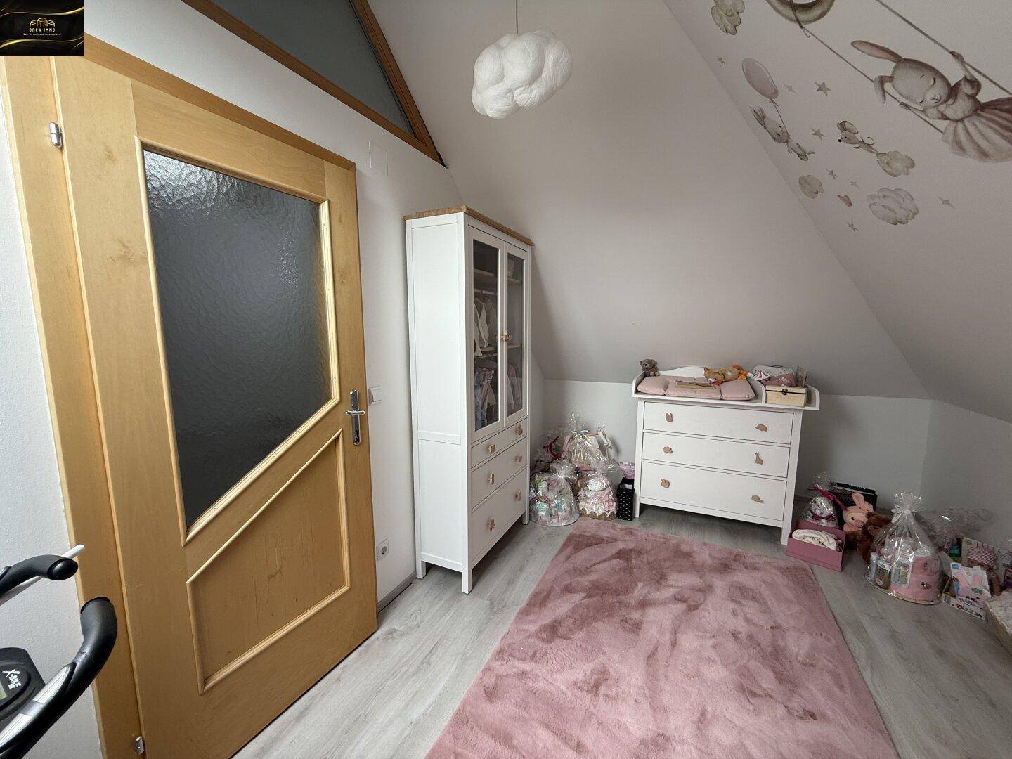 Kinderzimmer im Dachgeschoss mit schräger Decke, Teppich und kindgerechter Dekoration.