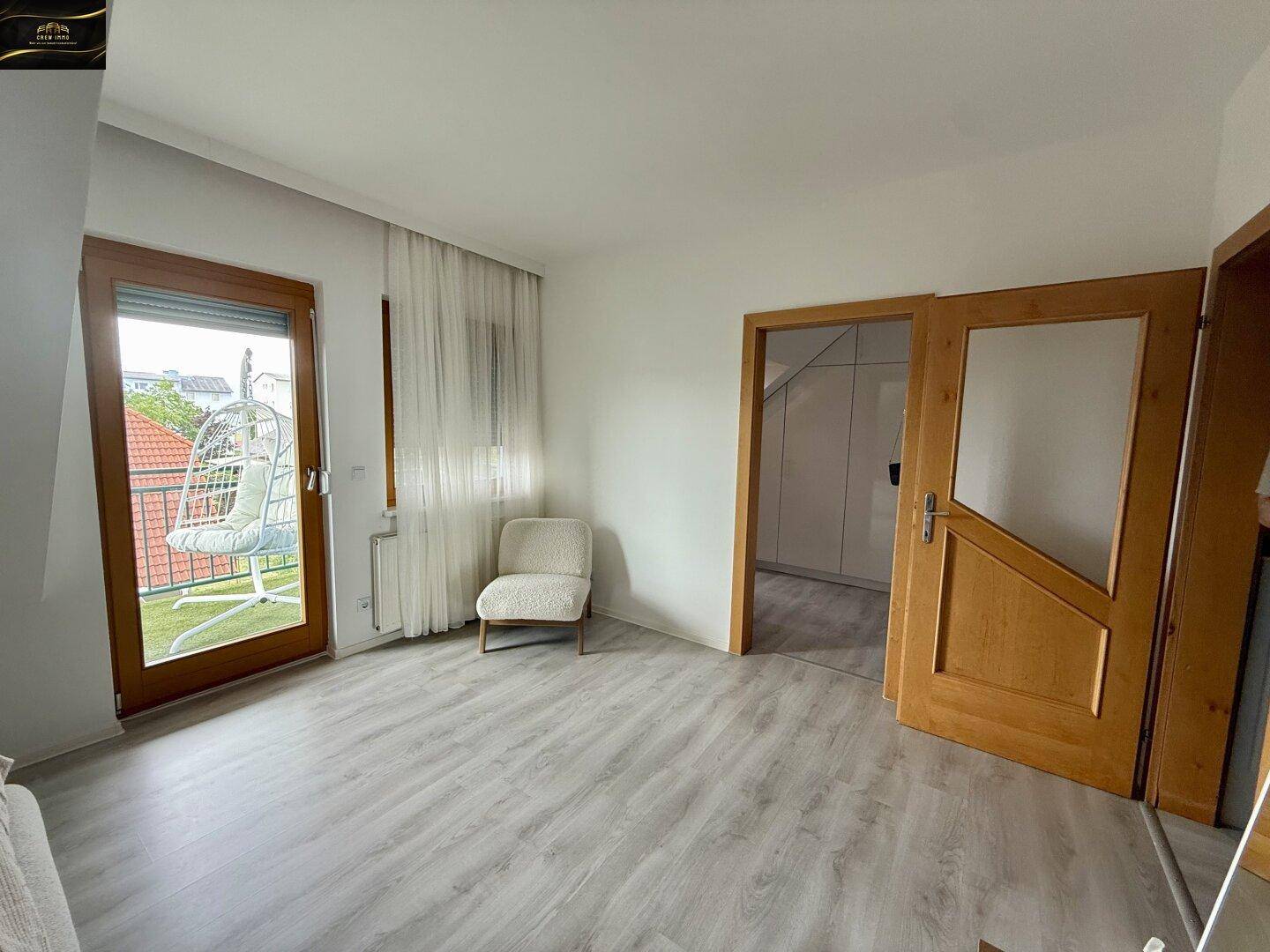 Schlafzimmer mit Zugang zu einem Balkon und einer Tür, die zu einem weiteren Raum führt.