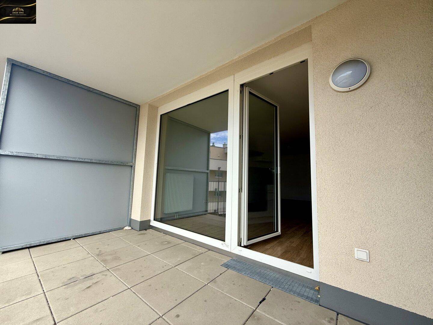 Geräumiger Balkon mit Fliesenboden und Blick auf die umliegenden Gebäude.