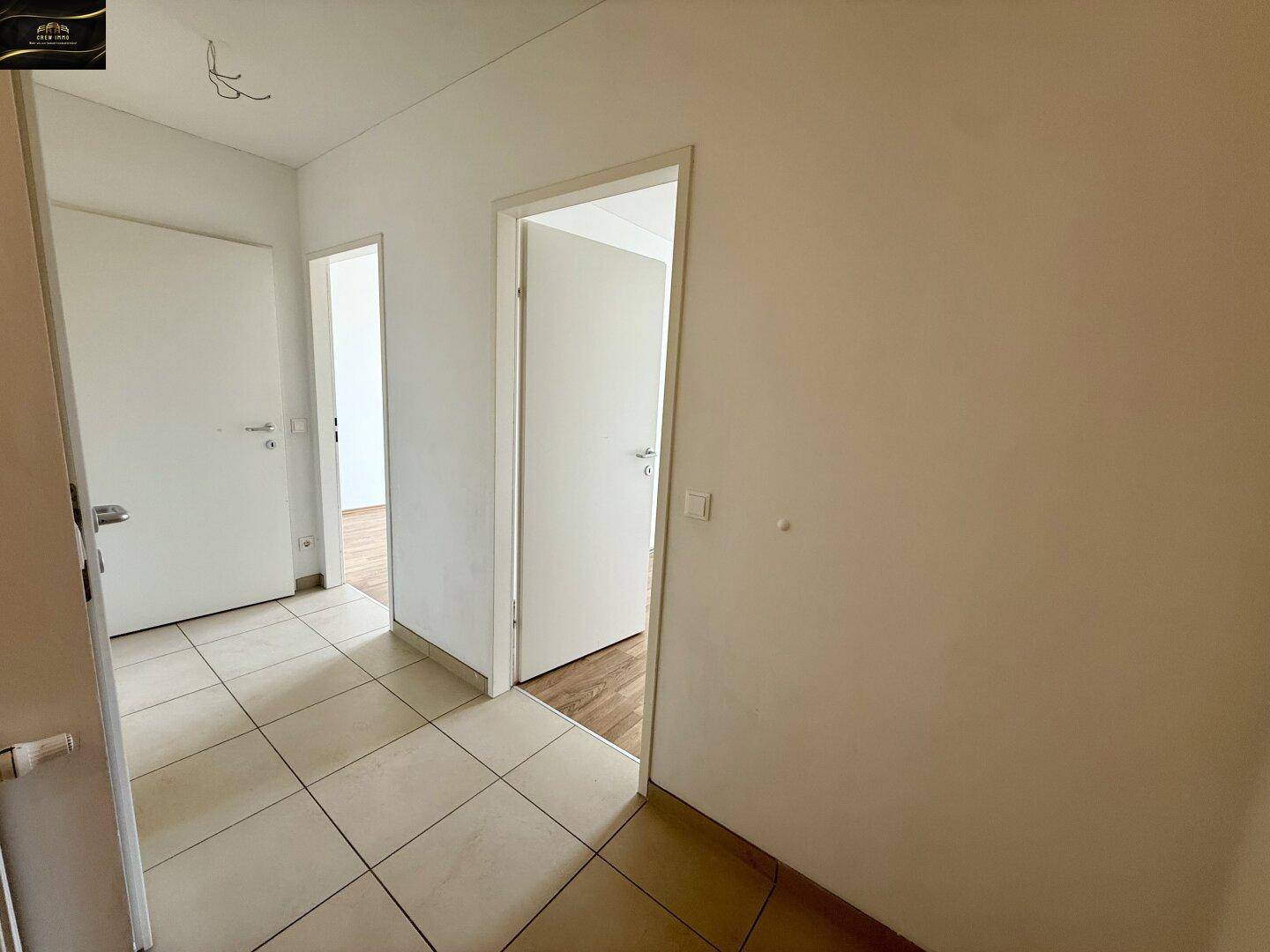 Heller Flur mit Fliesenboden und Zugang zu verschiedenen Zimmern der Wohnung.