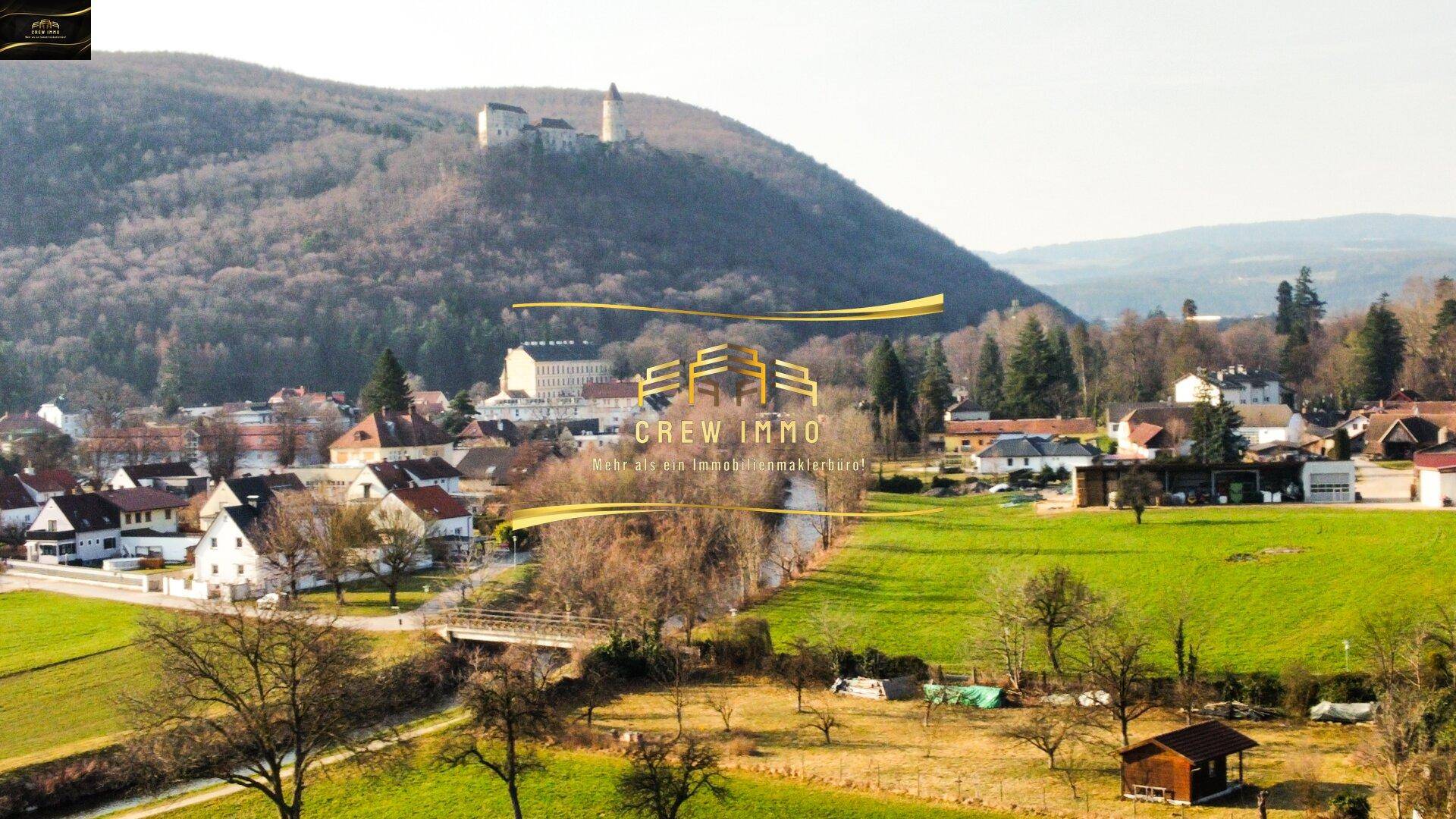 Malerische Landschaft mit grünen Hügeln, einem Fluss und einer Burg in der Ferne.