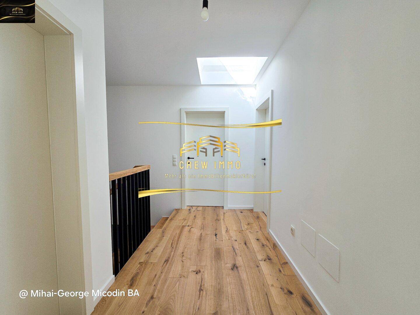 Heller Flur im Obergeschoss mit Holzboden und Dachfenster, das viel Tageslicht spendet.