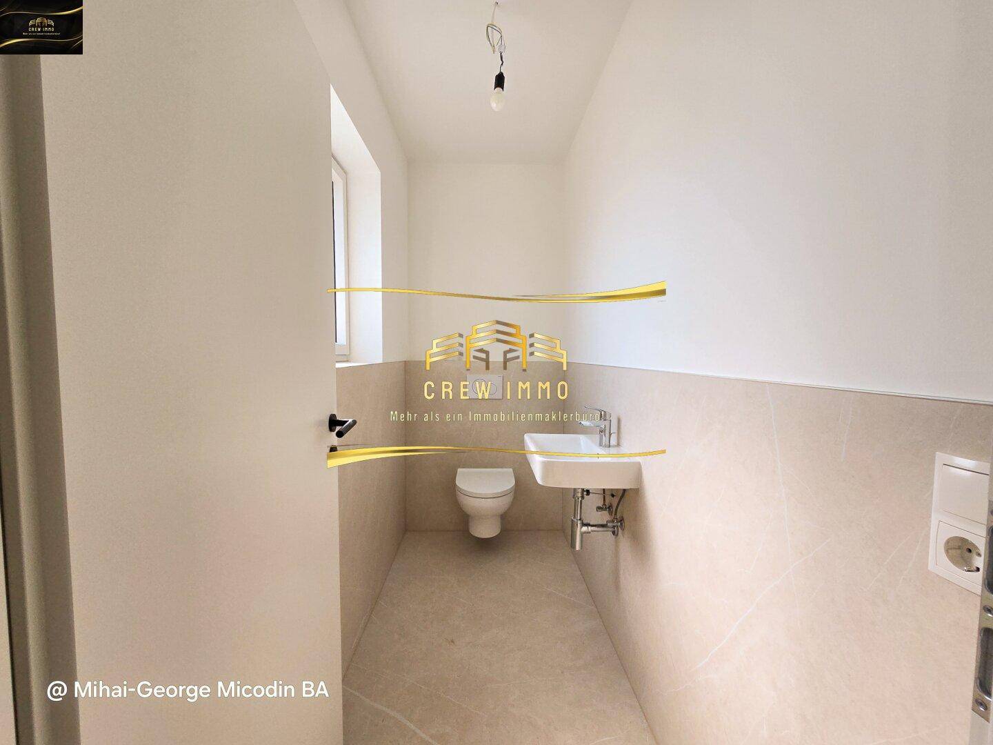 Modernes Gäste-WC mit Wand-WC, kleinem Waschbecken und hellen Fliesen.